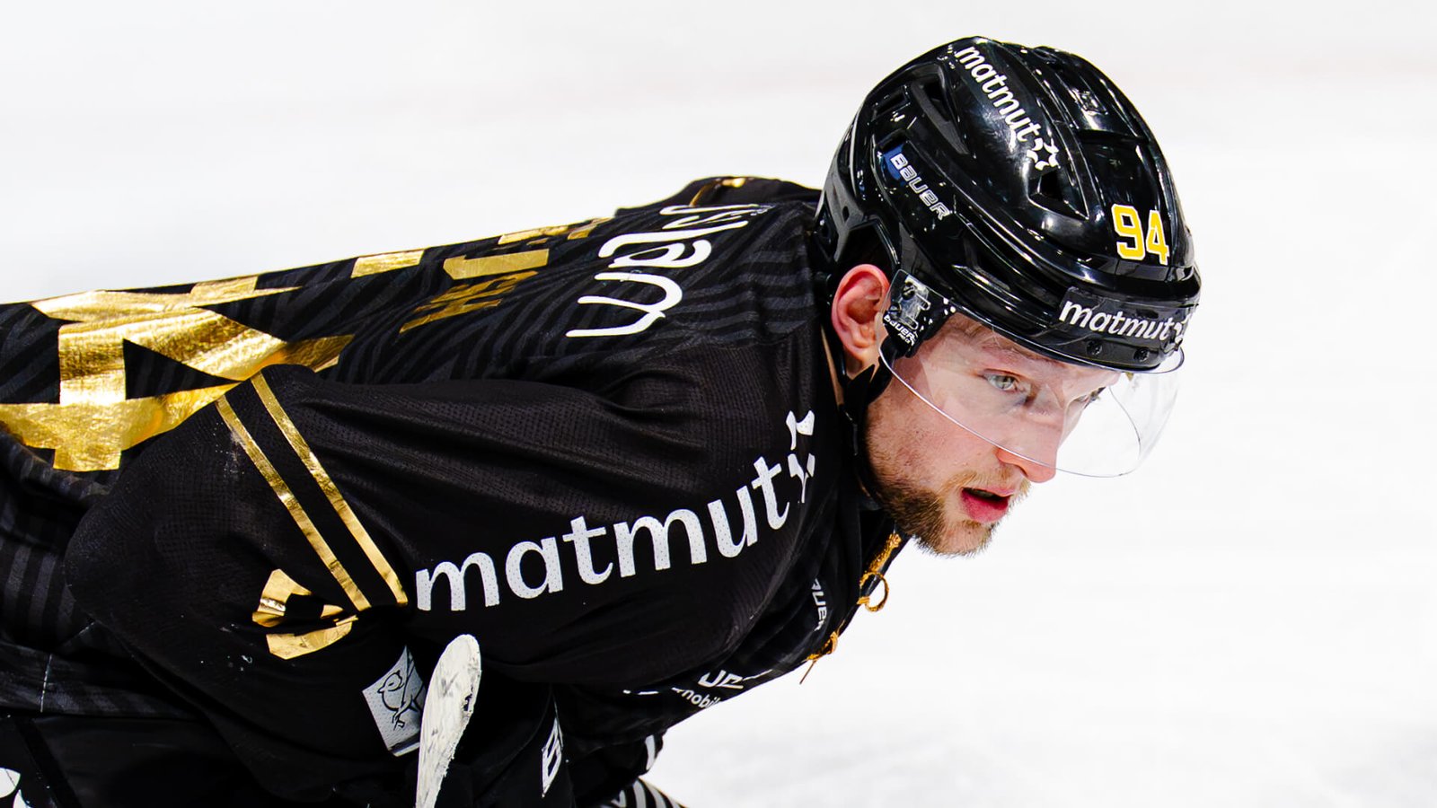 **Alt-Text:** Eishockeyspieler Michael Regush in schwarzem Trikot und schwarzem Helm auf dem Eis, konzentriert nach vorne blickend.