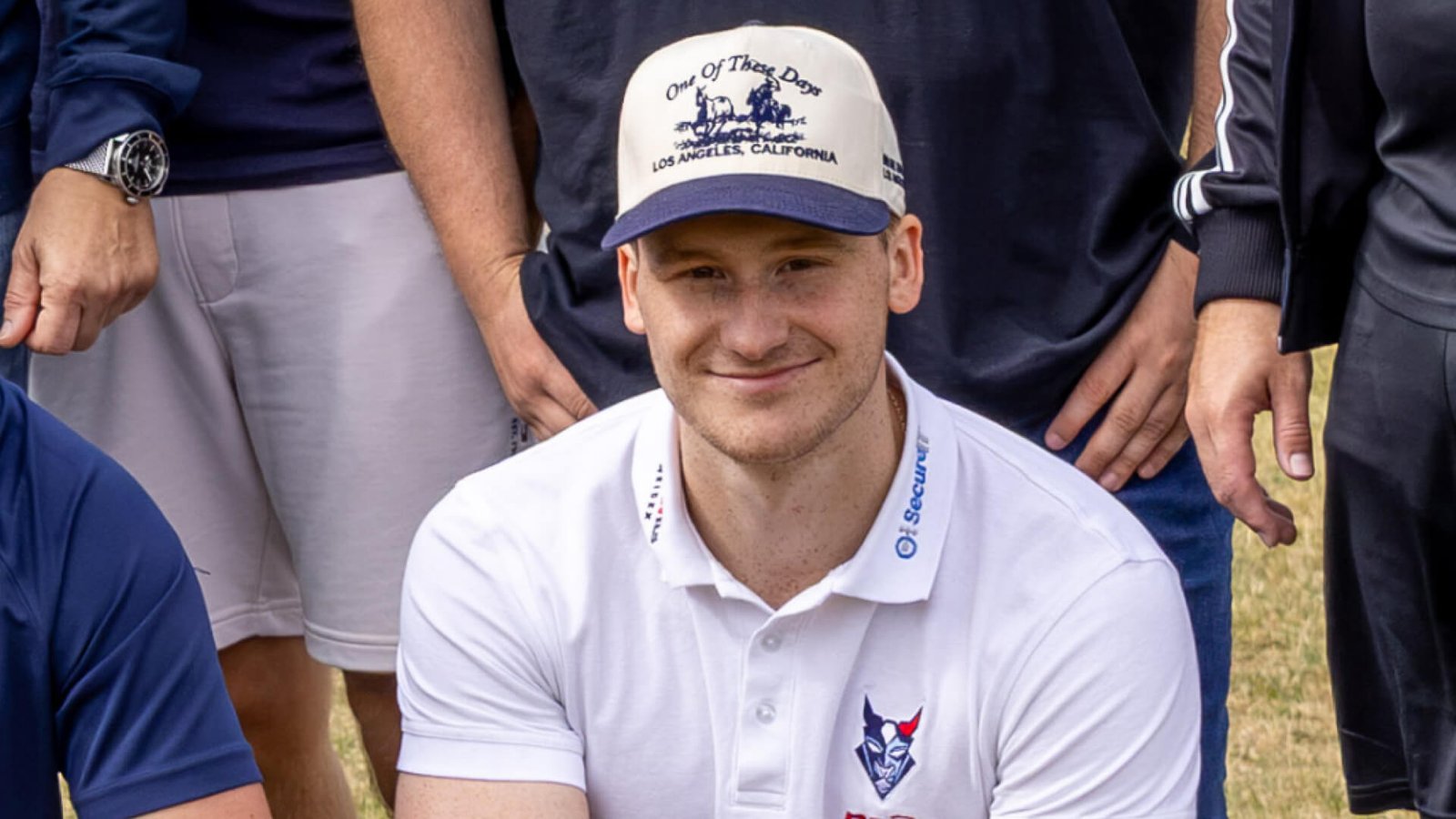 Philipp Faulhaber im weißen Poloshirt der Blue Devils Weiden und mit Baseballcap auf einem Mannschaftsfoto.